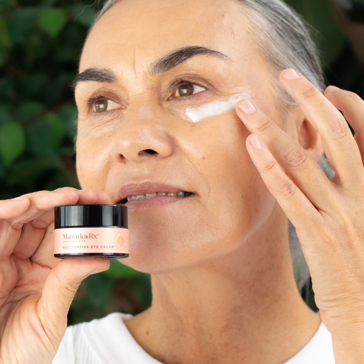 Woman applying ManukaRx Restorative Eye Cream to her face