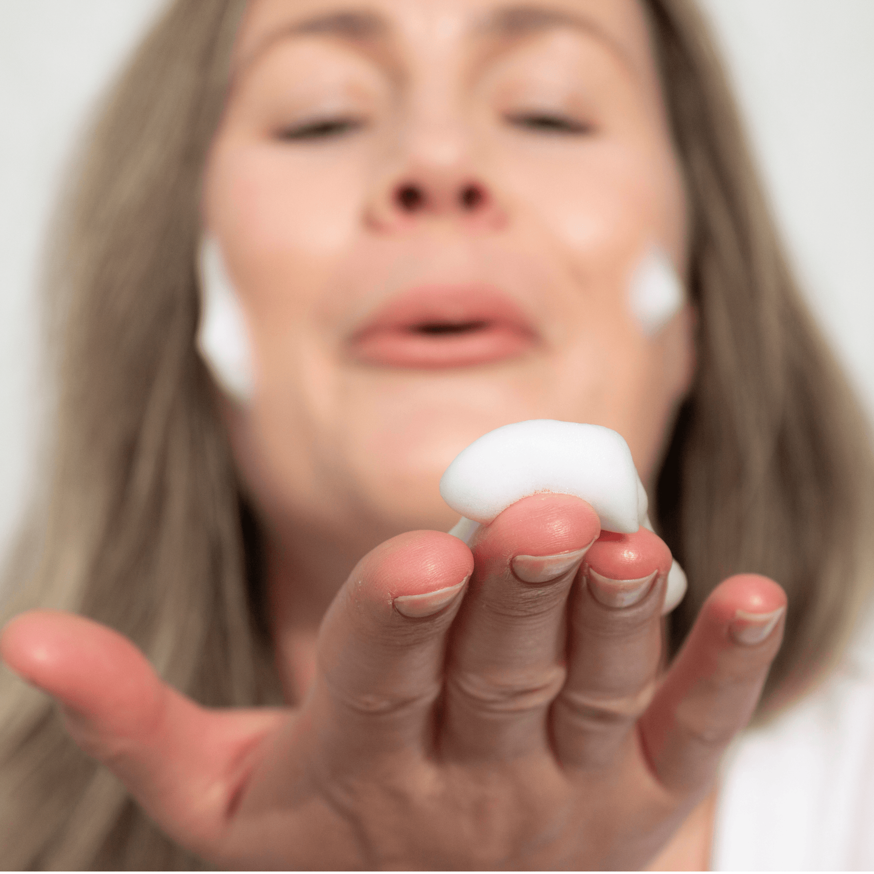 Woman with ManukaRX Foaming Face Wash Cleanser product on fingertips