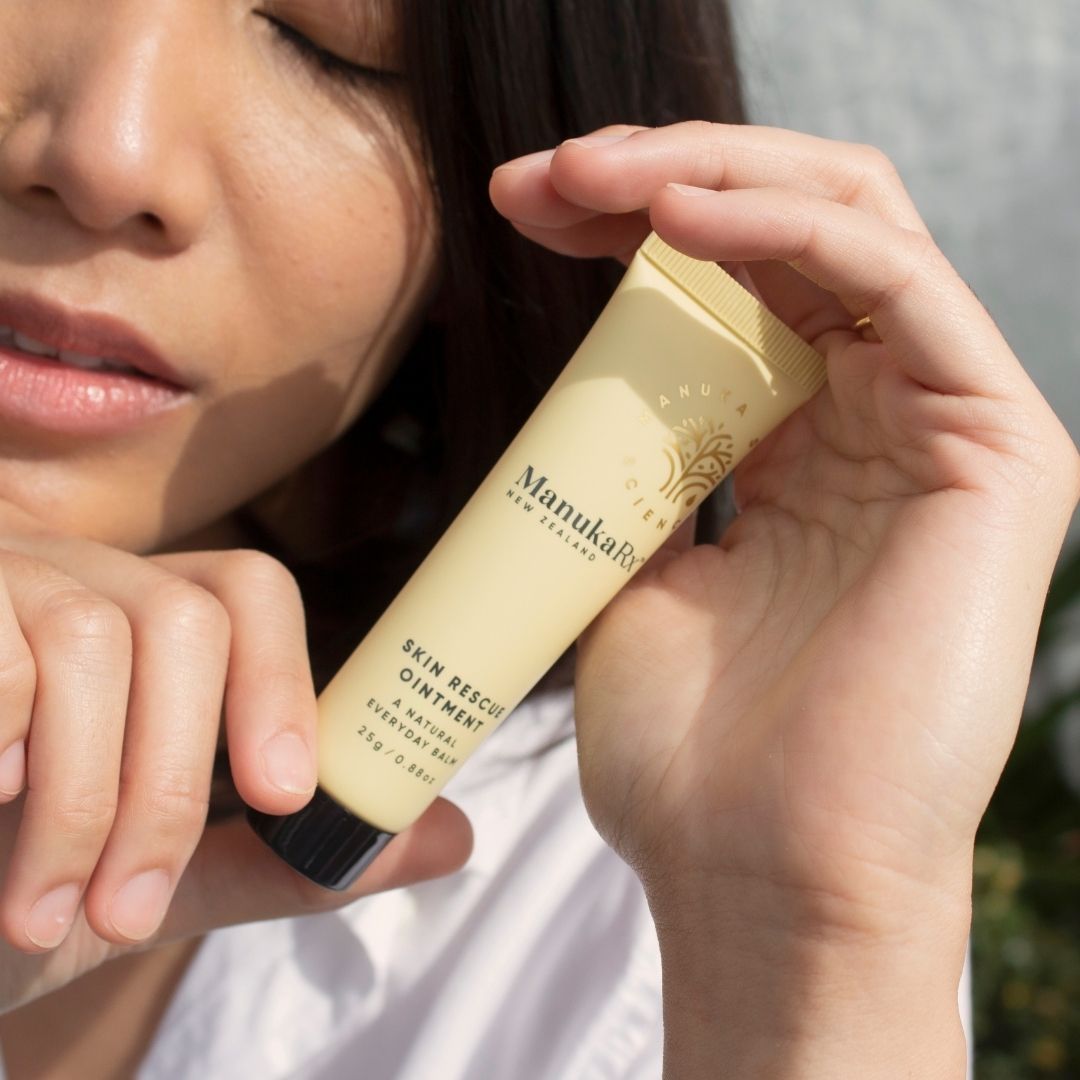 Woman holding tube of ManukaRx Skin Rescue Ointment