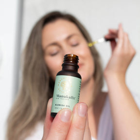 Woman holding bottle of ManukaRx Blemish Oil