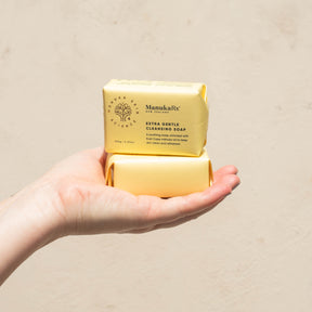 Hands holding two stacked bars of ManukaRx Extra Gentle Cleansing Soap