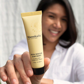 Woman holding tube of ManukaRx Skin Rescue Ointment